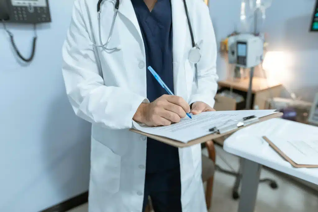 A doctor in a white coat writing down medical documents, such as coding.